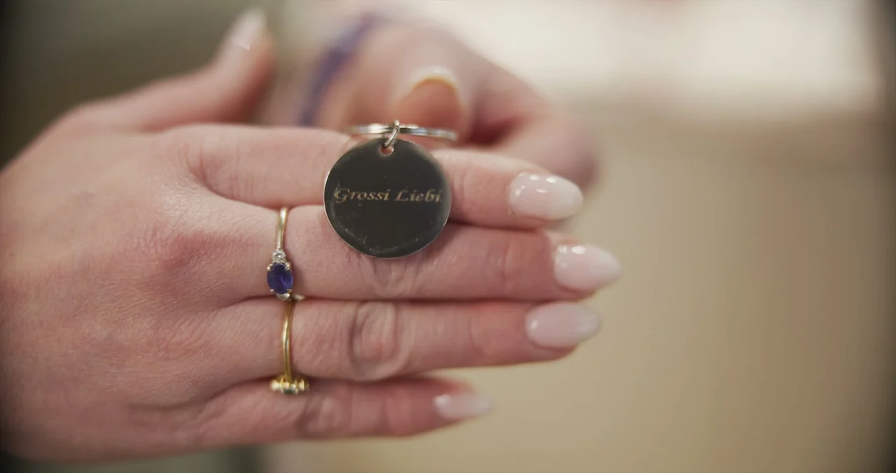 Schmuck-Anhänger Closeup mit Schweizer Dialekt-Gravur Grossi Liebi zwischen zwei Händen